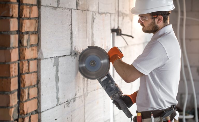 industrial-builder-works-with-professional-angle-grinder-cut-bricks-build-interior-walls-electrician
